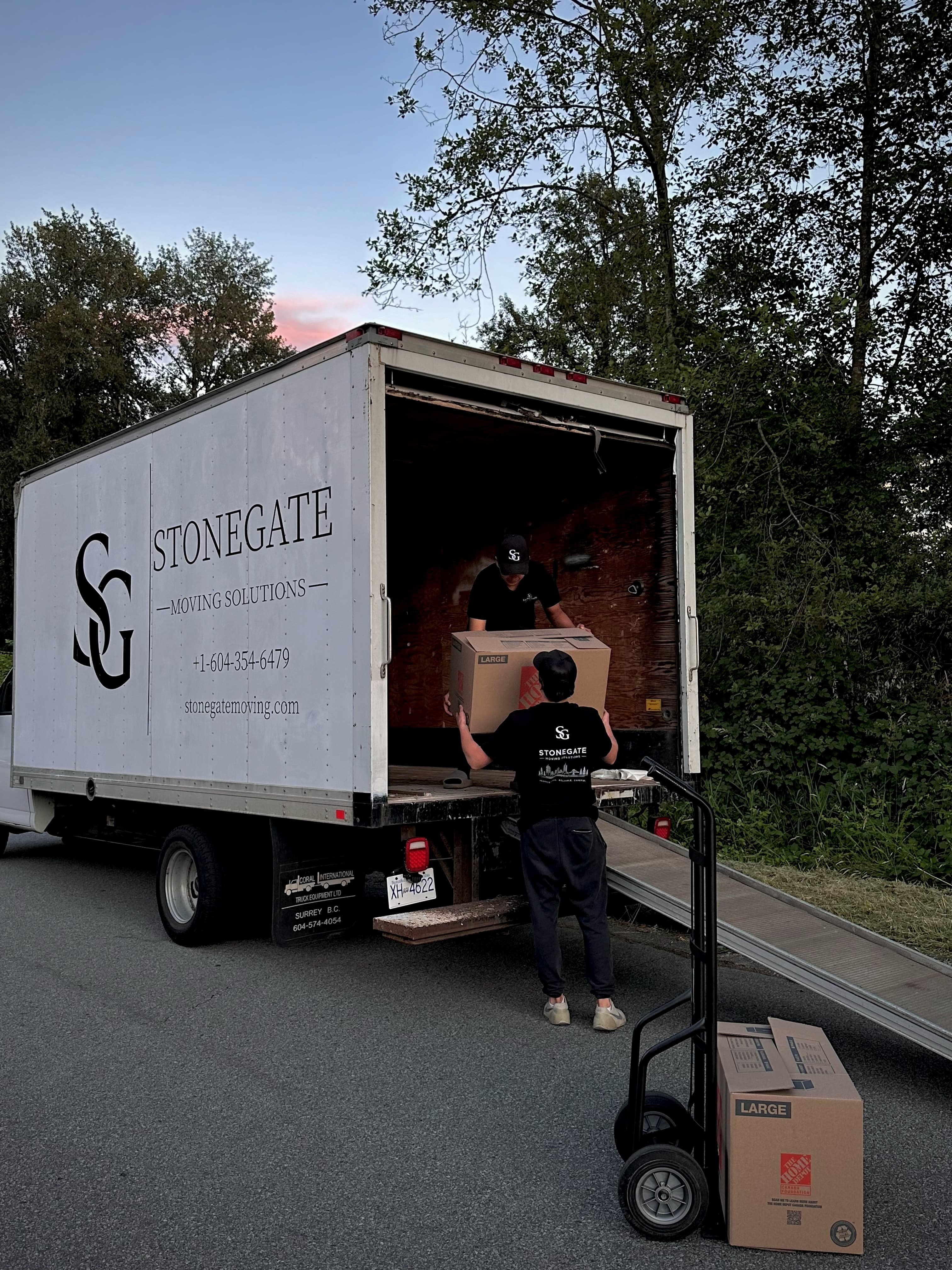 Two Stonegate movers lifting a box into the truck