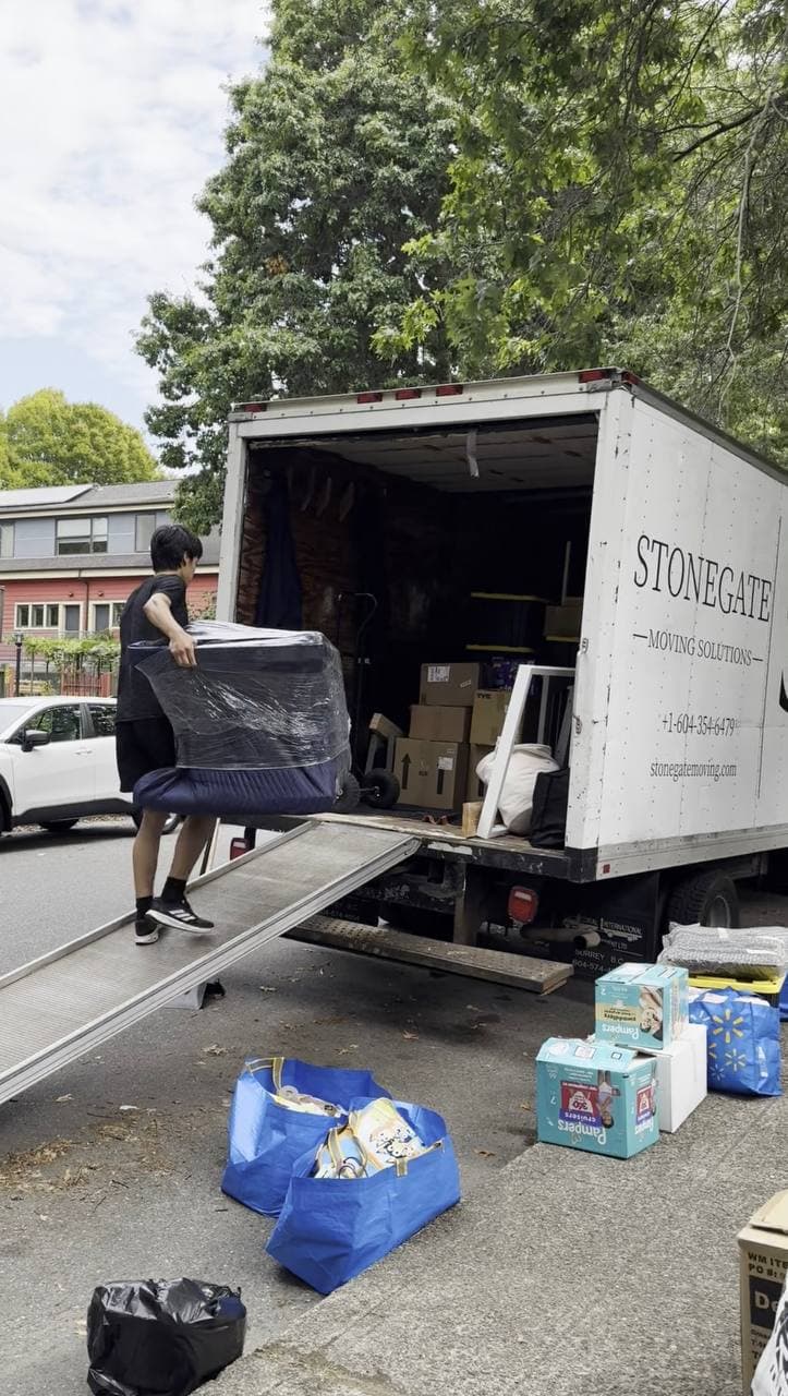 A Stonegate mover carrying wrapped furniture up the ramp into the truck